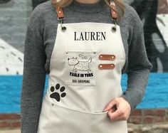 a woman wearing an apron with the words lauren written on it and a dog's paw