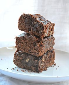 three pieces of chocolate brownie stacked on top of each other in front of a white plate