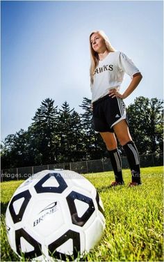 a woman standing next to a soccer ball