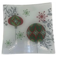 two christmas ornaments sitting on top of a glass plate with snowflakes in the background