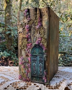 an old book with flowers growing out of it sitting on a doily covered table