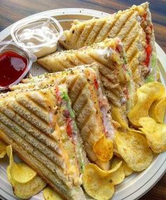 two sandwiches and chips on a plate with ketchup