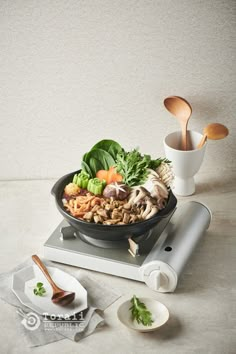 a bowl of food is sitting on top of a table with utensils and spoons