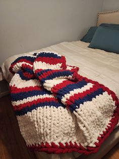 an unmade bed with a red, white and blue blanket on top of it