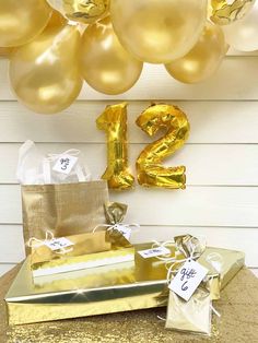 a table with gold foil balloons and presents under the number twenty two balloon garlands