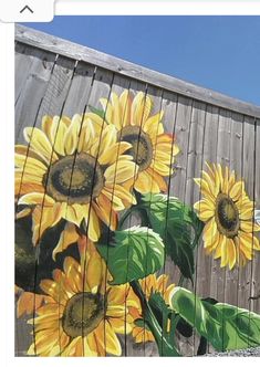 sunflowers painted on the side of a wooden fence