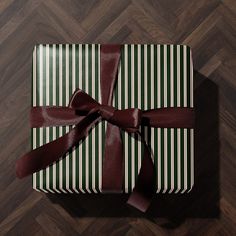 a present wrapped in green and white striped paper with a brown ribbon on top of it