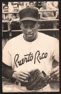 an old black and white photo of a baseball player holding a glove in front of a crowd