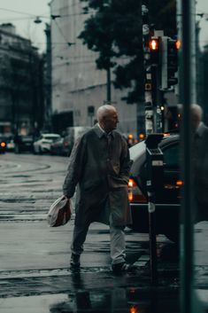 an old man walking down the street in the rain