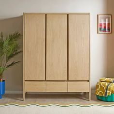 a wooden cabinet sitting next to a potted plant