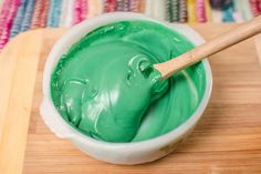 a white bowl filled with green paint and a wooden spoon