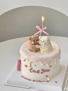 there is a cake with two teddy bears on it and a candle in the middle