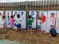 four children are painting pictures on the fence