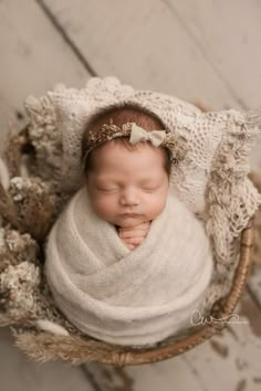 a newborn baby wrapped in a white blanket is curled up in a wicker basket