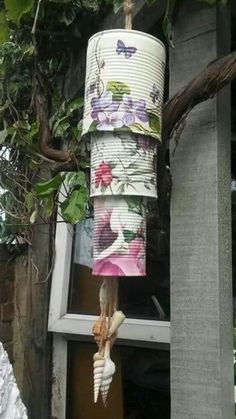 a lamp that is hanging from a tree in front of a window with flowers on it