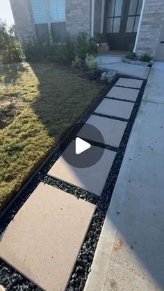 a walkway in front of a house with grass and rocks on the ground next to it