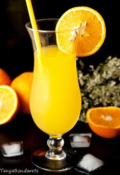 a glass filled with orange juice next to sliced oranges