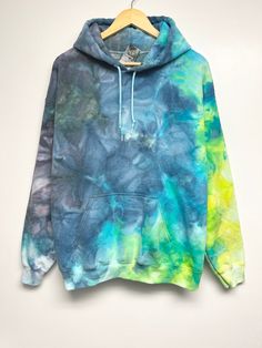 a blue and green tie dye hoodie hanging on a hanger