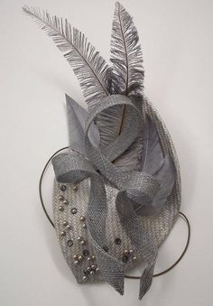 This is a 1930s inspired, leaf shaped silver grey hat. It is created with hand dyed silver straw, metallic glass pearls, dark grey diamante jewels, dip dyed ostrich arrowheads and a looping sinamay trim. This is a unique, entirely handmade piece suitable for formal summer events such as weddings or racing.The hat itself measures approx 12x18cm at the widest points and sits up to 14cm off the head including the feathers. It is held on with an elastic which sits comfortably at the nape of the neck Silver Fitted Fascinator For Evening, Spring Silver Adjustable Fascinator, Silver Formal Hat Fascinator, Luxury Silver Elegant Fascinator, Elegant Silver Adjustable Fascinator, Carnival Headdress, Grey Fascinator, Small Hats, Beaded Headpiece