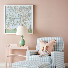 a blue and white chair sitting in front of a pink wall with a painting on it