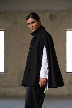 Introducing our Handmade Black Wool Cape - a true masterpiece of craftsmanship, designed to elevate your winter wardrobe to new heights. Meticulously crafted from 100% high-quality sheep wool, this cape is a testament to both warmth and style. With its unique poncho construction, this cape offers a contemporary twist on traditional winter outerwear. It features carefully designed openings for the arms, allowing for freedom of movement without compromising on coziness. The hidden button closure a Elegant Oversized Wool Poncho, Elegant Fall Poncho For Work, Elegant Fall Poncho For Workwear, Elegant Fall Workwear Poncho, Elegant Wool Poncho For Workwear, Classic Wool Cape For Winter, Modern Winter Cape Outerwear, Long Wool Cape For Fall, Wool Long Coat Cape For Fall