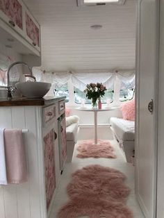 the interior of a camper with pink rugs on the floor and white walls