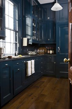 a kitchen with blue cabinets and wooden floors is shown in this image, the light shines through the window