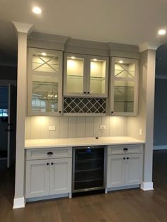 an empty kitchen with white cabinets and wood floors