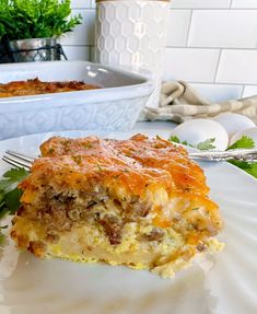 a piece of quiche on a plate with a fork and bowl in the background