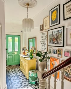 an entry way with pictures on the wall and green door in the center, next to a yellow chest of drawers