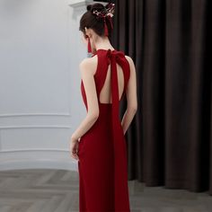 a woman in a red dress with a bow on her head looking at the mirror