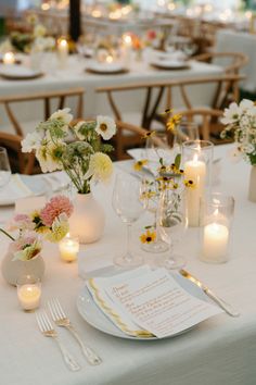 the table is set with candles and flowers in vases, plates and napkins