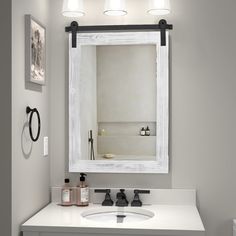 a bathroom with a sink, mirror and lights on the wall above it's counter