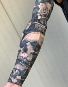 a man's arm with a skull and roses tattoo on the left side of his arm