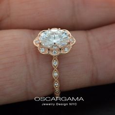 a close up of a person's hand holding an engagement ring with a diamond