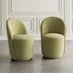 two green chairs sitting side by side in front of a wall with white paneling