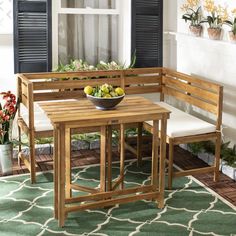 a wooden table with two chairs and a bowl of fruit on it in front of a window