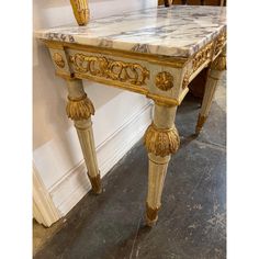 an antique marble top table with gold trimmings and ornate carvings on the legs