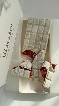 an open box with pieces of white chocolate and blood on the inside, sitting on a table