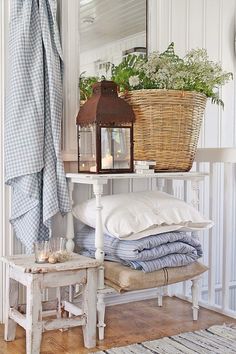 a white shelf with pillows, blankets and a basket on it next to a mirror