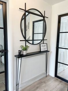 a mirror on the wall above a table with a potted plant next to it