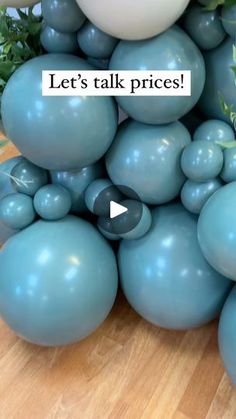 a bunch of blue balloons sitting on top of a wooden table next to a plant