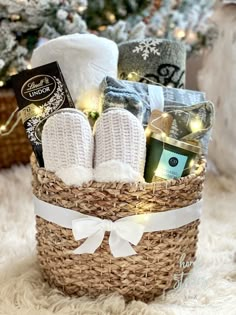 a basket filled with lots of items sitting on top of a white rug next to a christmas tree