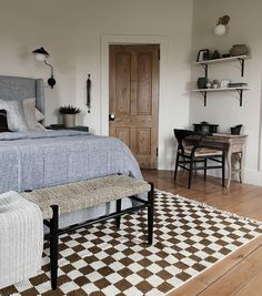 a bed sitting on top of a wooden floor next to a white and brown rug