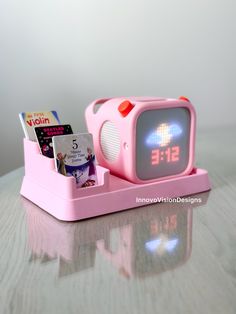 a pink alarm clock sitting on top of a table