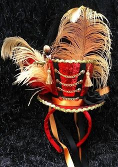 a red and black hat with feathers on it's head, sitting against a black background