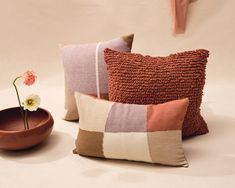 three pillows and a bowl with a flower in it