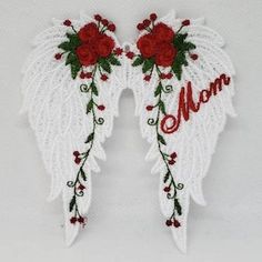 two white angel wings with red flowers and the word mom written on one side in script