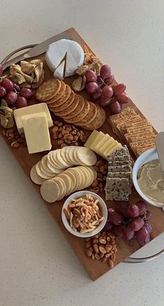 a wooden platter filled with cheese, crackers and nuts