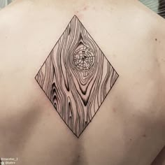 the back of a man's shoulder with a piece of wood and compass tattoo on it